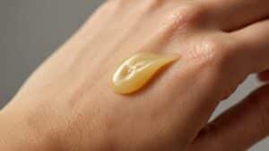 A close-up of a hand applying a finished beeswax salve, showing a rich texture and healthy skin.