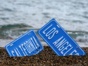 two signs in the sand saying California and Los Angeles