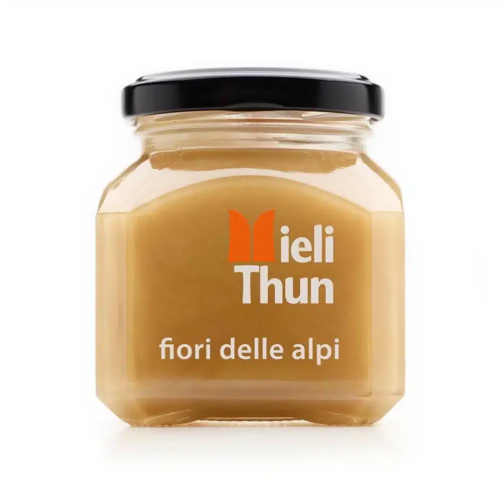 Glass jar of Meili Thun Alpine Flowers Honey labeled “fiori delle alpi,” with a black lid, on a white background.